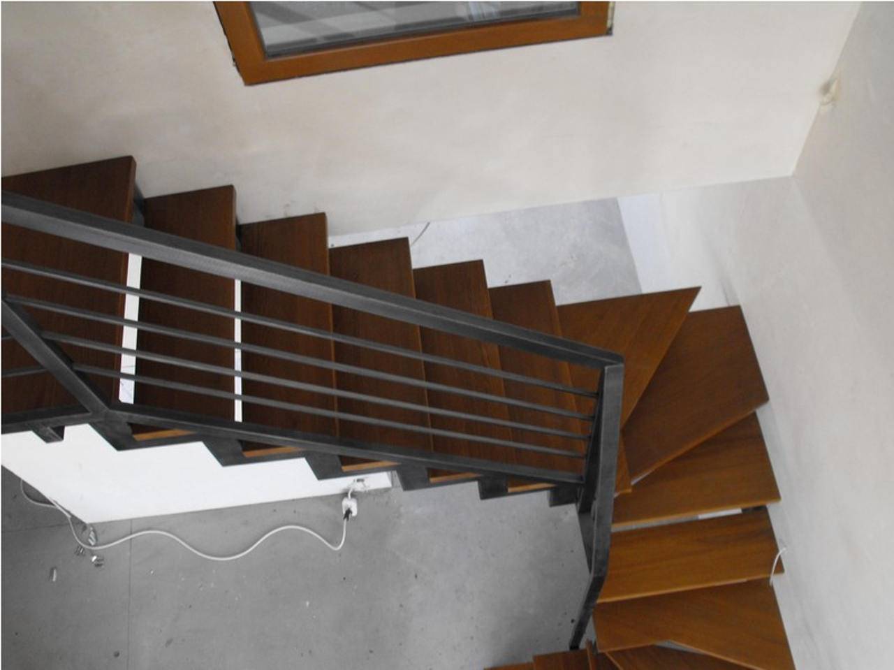 Drewniane schody z metalową, ciemną balustradą w stylu industrialnym