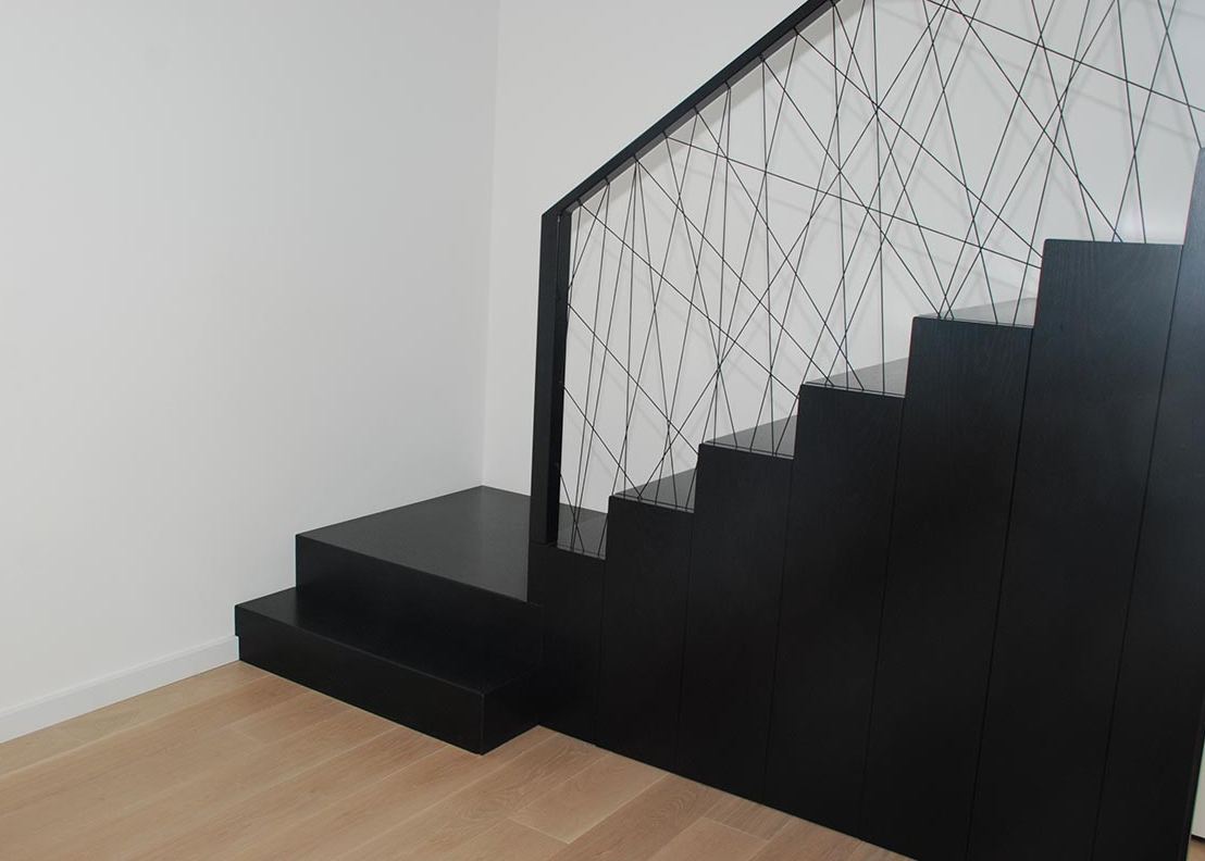 Proste schody czarne z artystyczną balustradą industrialną