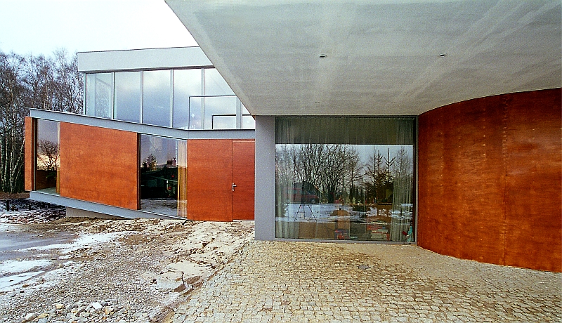 Dom o geometrycznej bryle -  połączenie elewacji betonowej z drewnem 